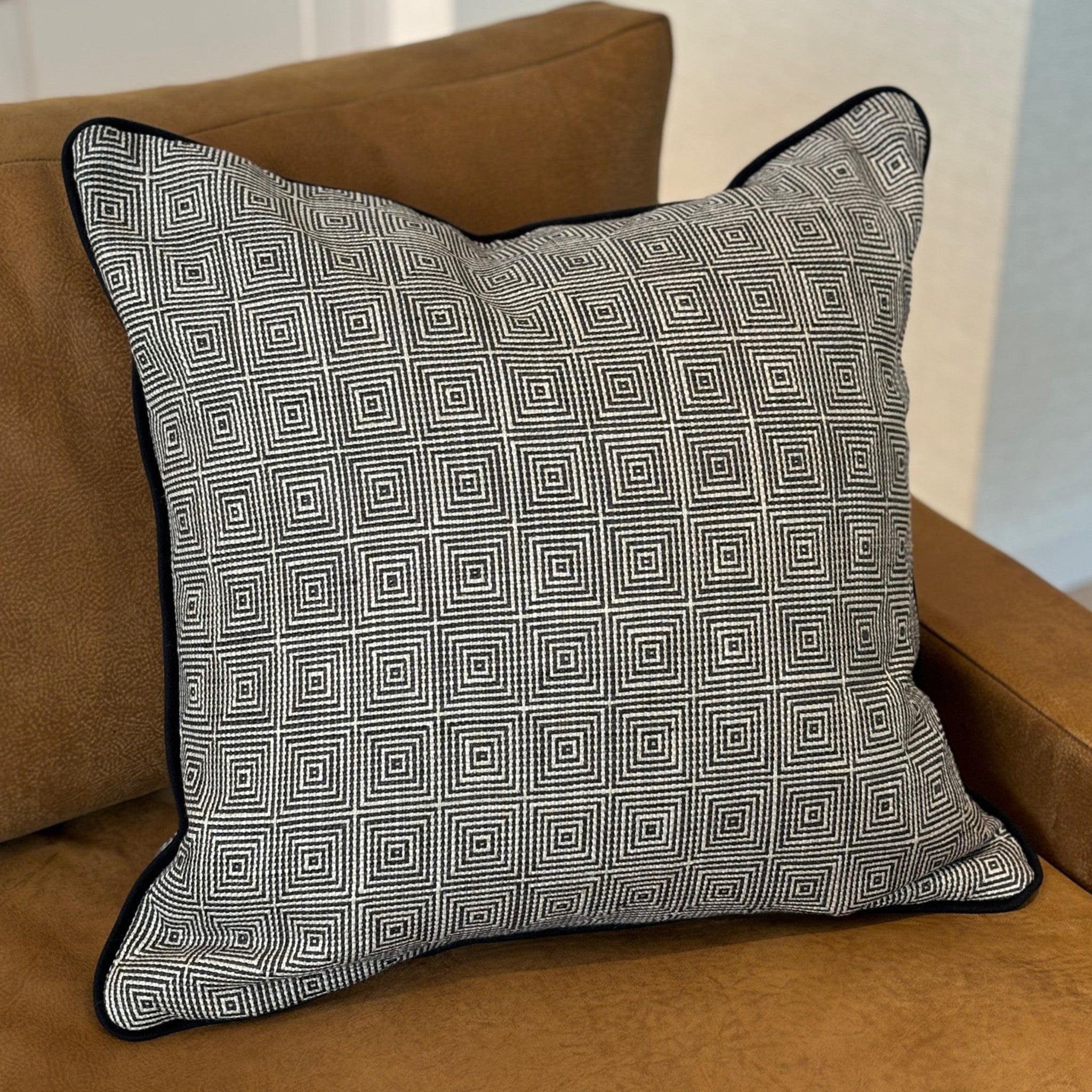 Luxury cushion in a black and white geometric pattern, with black piping. A plump feather inner cushion is included. Our made to order cushions are plump and cosy. Dimensions: 600 x 600 mm Made to order in approx 3 weeks